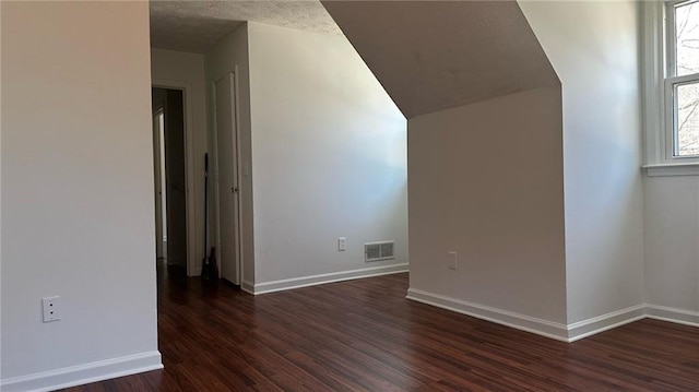 additional living space featuring visible vents, baseboards, and dark wood-style flooring