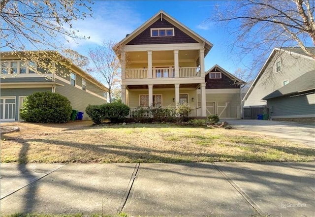 view of front of property with covered porch, driveway, a front lawn, and a balcony
