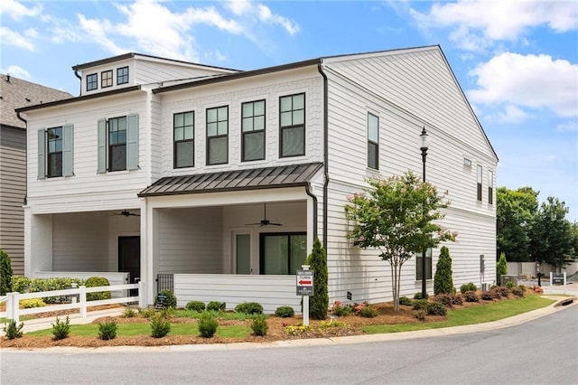 view of front facade featuring fence, a ceiling fan, a standing seam roof, and metal roof