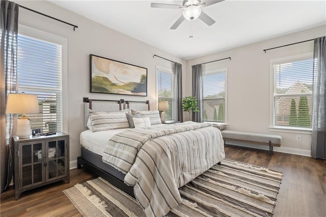 bedroom with baseboards, wood finished floors, and multiple windows