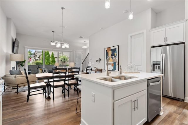 kitchen with white cabinets, a sink, stainless steel appliances, a ceiling fan, and wood finished floors