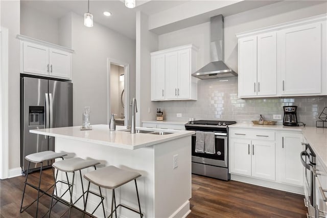 kitchen with stainless steel appliances, decorative backsplash, a sink, and wall chimney exhaust hood