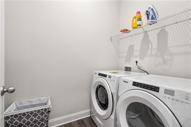 clothes washing area featuring separate washer and dryer, laundry area, baseboards, and dark wood-type flooring