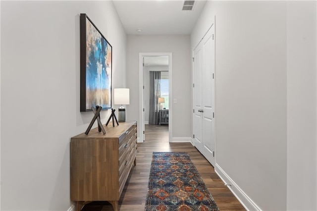 hall featuring baseboards, dark wood-type flooring, and visible vents