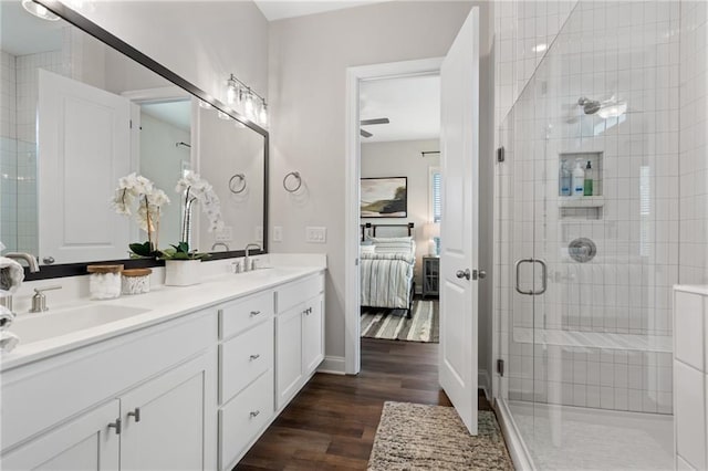 ensuite bathroom featuring double vanity, wood finished floors, ensuite bathroom, a shower stall, and a sink