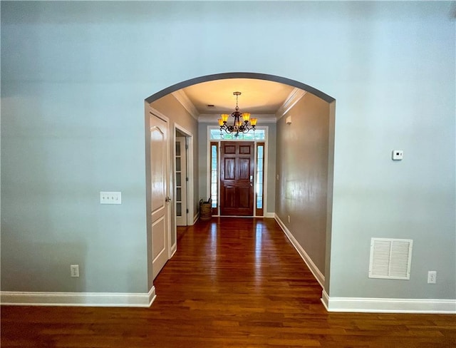 foyer featuring dark hardwood / wood-style floors, ornamental molding, and a chandelier