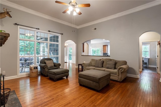 living room featuring a towering ceiling, hardwood / wood-style flooring, ceiling fan, and crown molding