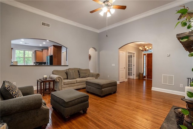 living room featuring ceiling fan with notable chandelier, light wood-type flooring, and crown molding