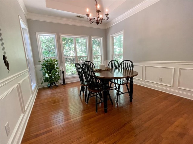 dining room featuring a chandelier, dark hardwood / wood-style flooring, a raised ceiling, and ornamental molding