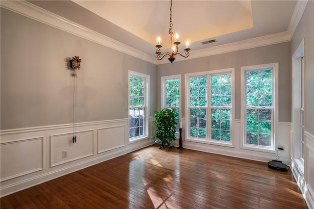 unfurnished room featuring a raised ceiling, dark hardwood / wood-style flooring, ornamental molding, and an inviting chandelier