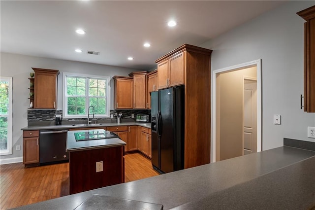 kitchen featuring dishwasher, decorative backsplash, sink, and black refrigerator with ice dispenser