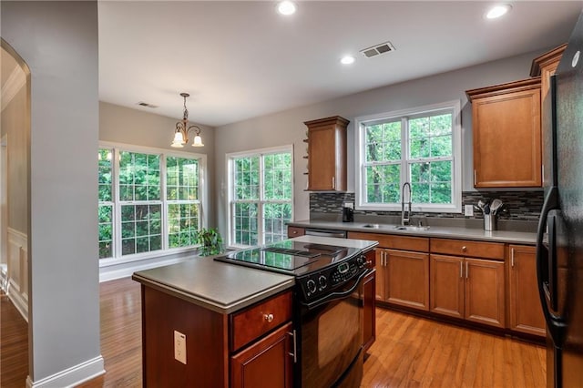 kitchen featuring sink, a center island, an inviting chandelier, pendant lighting, and black appliances