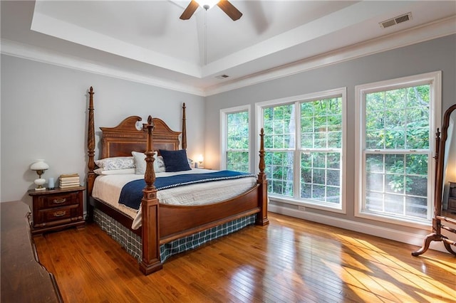 bedroom featuring a tray ceiling, ceiling fan, crown molding, and hardwood / wood-style flooring