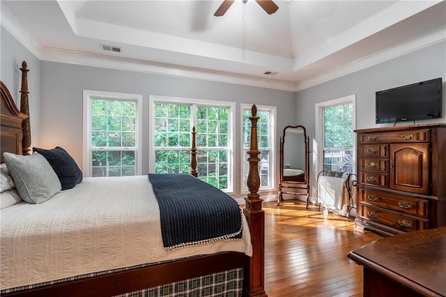 bedroom featuring a tray ceiling, ceiling fan, light hardwood / wood-style floors, and ornamental molding