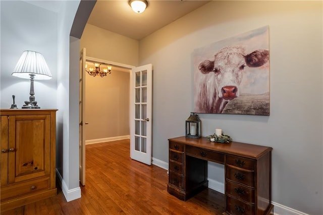 hallway featuring a chandelier, wood-type flooring, and french doors