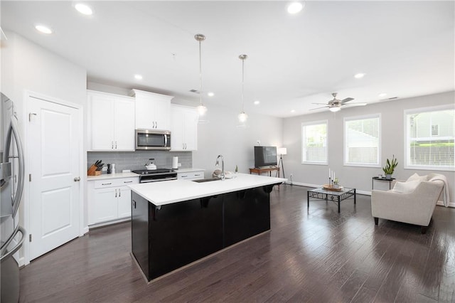 kitchen featuring appliances with stainless steel finishes, a kitchen island with sink, ceiling fan, sink, and white cabinetry