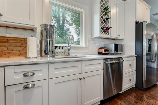 2972 Lookout Pl NE, Atlanta, GA 30305 - kitchen with appliances with stainless steel finishes, white cabinetry, tasteful backsplash, light stone countertops, and dark wood-style floors