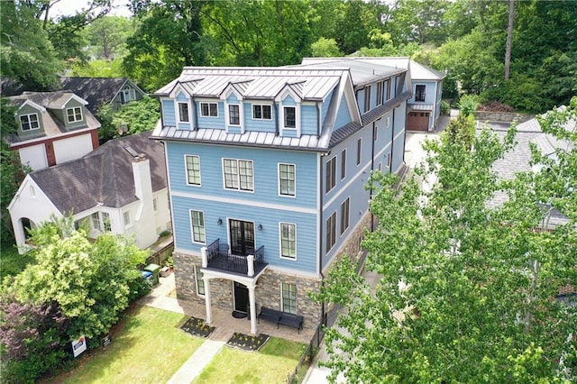 2972 Lookout Pl NE, Atlanta, GA 30305 - view of front of property with a standing seam roof, a balcony, a metal roof, stone siding, and view of wooded area