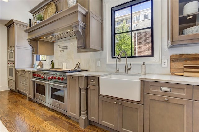 2972 Lookout Pl NE, Atlanta, GA 30305 - kitchen with range with two ovens, decorative backsplash, light countertops, dark wood-style flooring, and custom exhaust hood