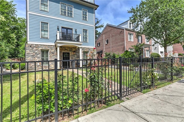 2972 Lookout Pl NE, Atlanta, GA 30305 - view of front facade with a balcony, a fenced front yard, stone siding, and a porch