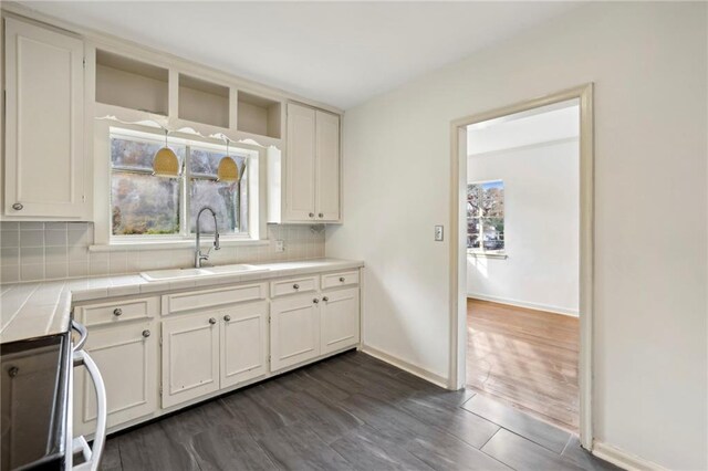 kitchen with tile counters, sink, dark hardwood / wood-style flooring, decorative backsplash, and white cabinets