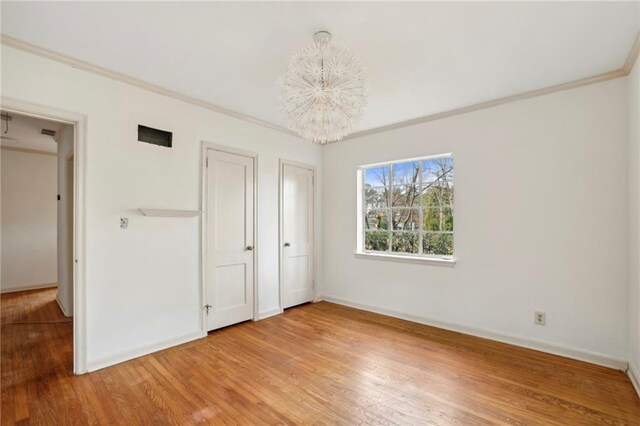 unfurnished bedroom featuring wood-type flooring, an inviting chandelier, and ornamental molding