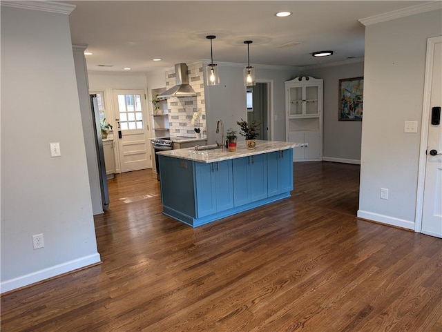 kitchen featuring pendant lighting, dark wood-type flooring, sink, wall chimney exhaust hood, and appliances with stainless steel finishes