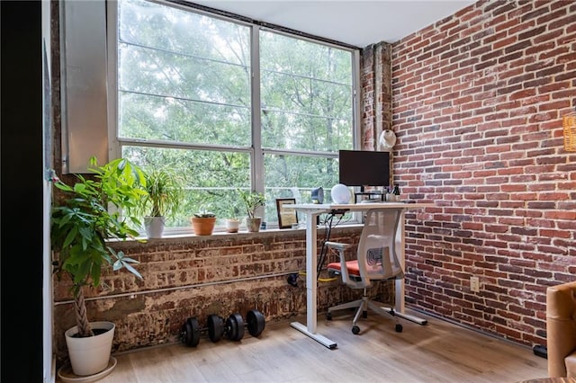 office with a healthy amount of sunlight, brick wall, and wood finished floors