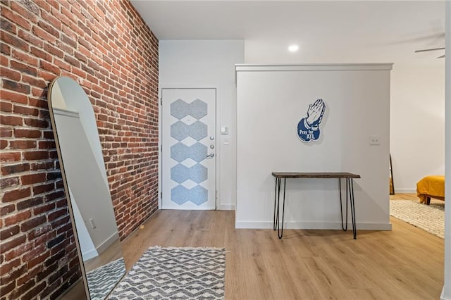 entryway featuring baseboards, light wood-style floors, brick wall, and arched walkways