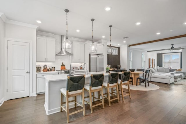 5217 Riden Ct Unit 263, Buford, GA 30518 - kitchen featuring built in refrigerator, wall chimney exhaust hood, ornamental molding, dark wood-type flooring, and a center island with sink
