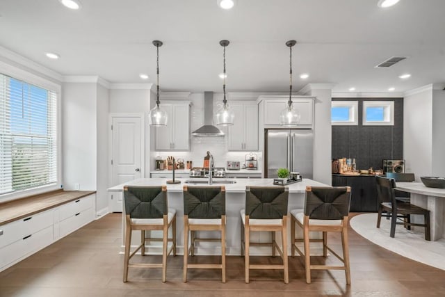 5217 Riden Ct Unit 263, Buford, GA 30518 - kitchen featuring wall chimney range hood, high end fridge, ornamental molding, light countertops, and a kitchen breakfast bar