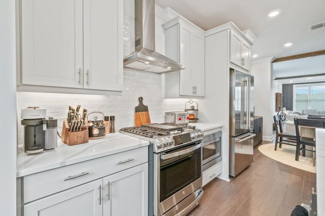 5217 Riden Ct Unit 263, Buford, GA 30518 - kitchen with wall chimney exhaust hood, stainless steel appliances, light countertops, backsplash, and wood finished floors