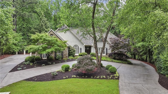 view of front of home with curved driveway, a front yard, and stone siding