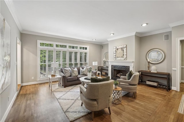 living area with wood finished floors, recessed lighting, a premium fireplace, crown molding, and baseboards