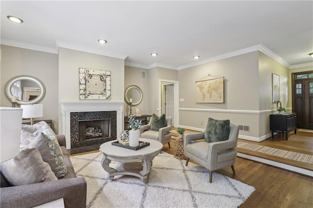 living room with wood finished floors, recessed lighting, baseboards, crown molding, and a fireplace