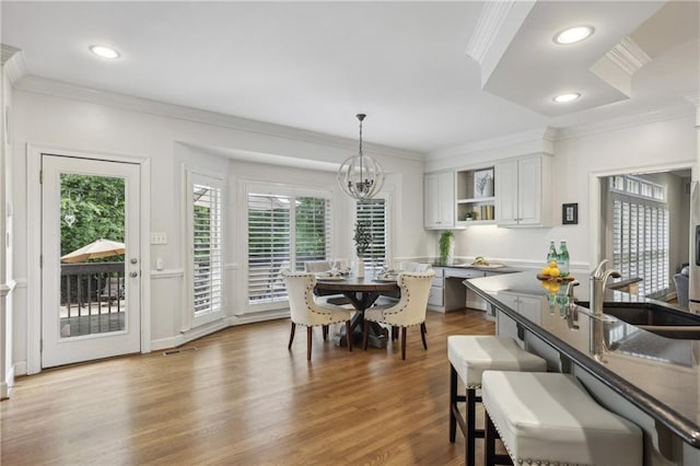 dining space with ornamental molding, healthy amount of natural light, wood finished floors, a chandelier, and recessed lighting