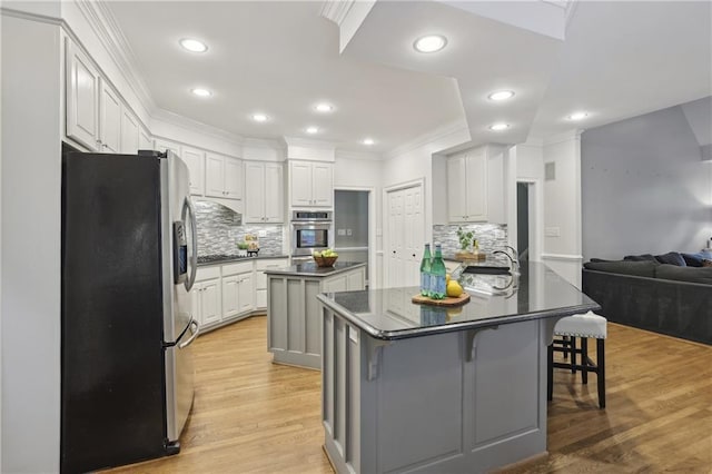kitchen featuring appliances with stainless steel finishes, dark countertops, a kitchen island, ornamental molding, and tasteful backsplash