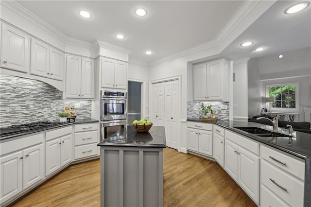 kitchen featuring double oven, a sink, gas cooktop, recessed lighting, and ornamental molding