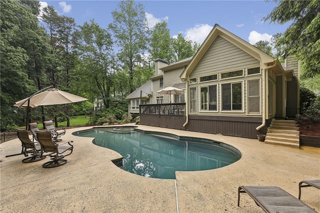 outdoor pool featuring a deck, a patio area, and a sunroom
