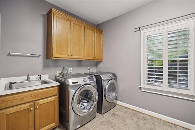 clothes washing area with cabinet space, separate washer and dryer, and baseboards