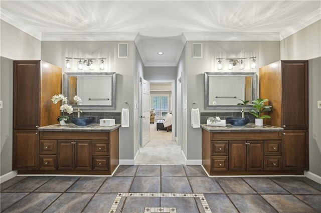 bathroom featuring baseboards, decorative backsplash, two vanities, crown molding, and ensuite bathroom