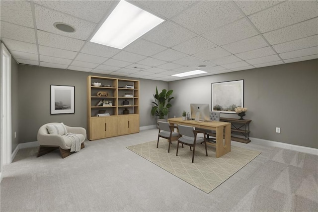office area with light carpet, a paneled ceiling, and baseboards