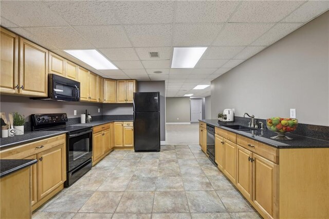 kitchen with black appliances, a sink, a paneled ceiling, and baseboards