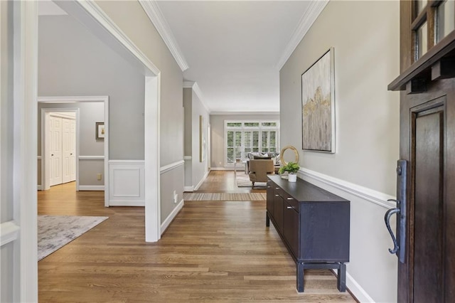 hall with ornamental molding and wood finished floors