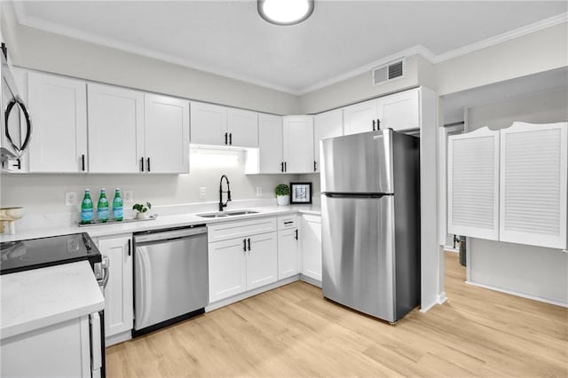 kitchen with stainless steel appliances, ornamental molding, a sink, and white cabinets