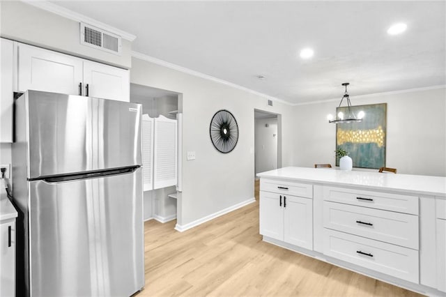 kitchen featuring light wood-style flooring, visible vents, white cabinets, freestanding refrigerator, and crown molding