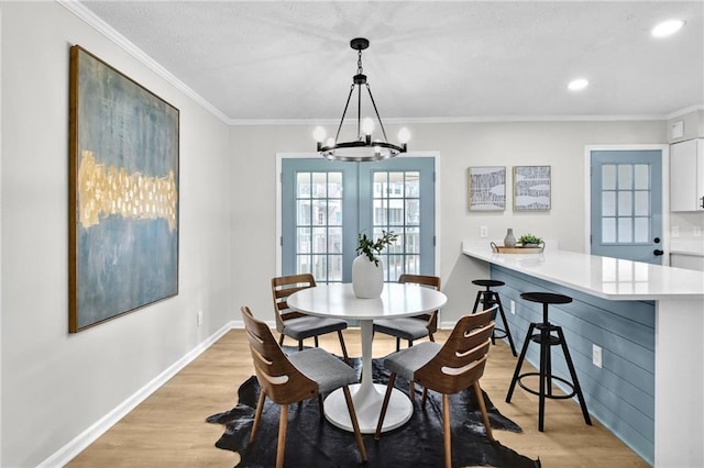 dining room with light wood-style flooring and crown molding