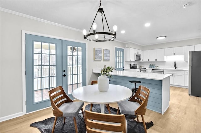 dining space with french doors, light wood finished floors, and crown molding