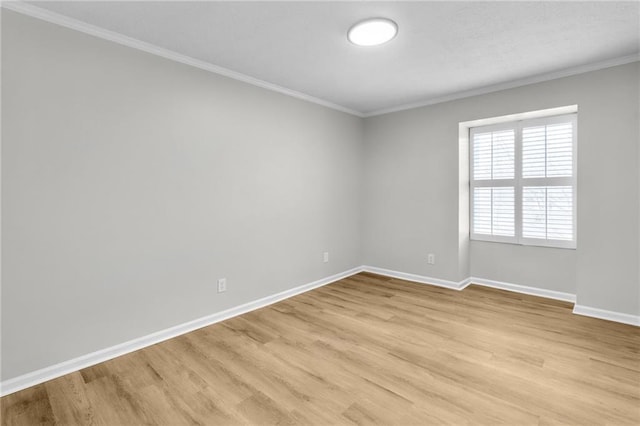 empty room with crown molding, light wood-style flooring, and baseboards