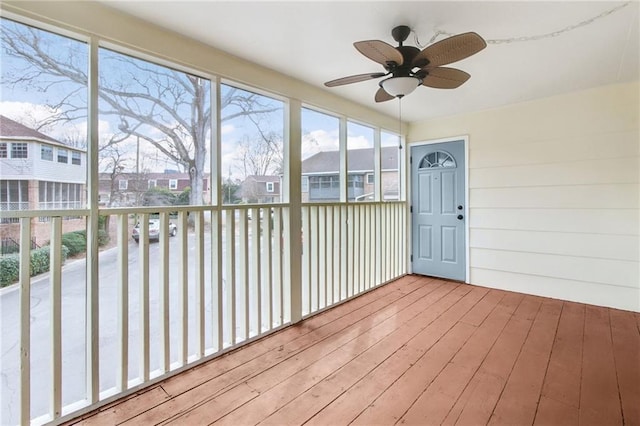 unfurnished sunroom featuring ceiling fan and a residential view